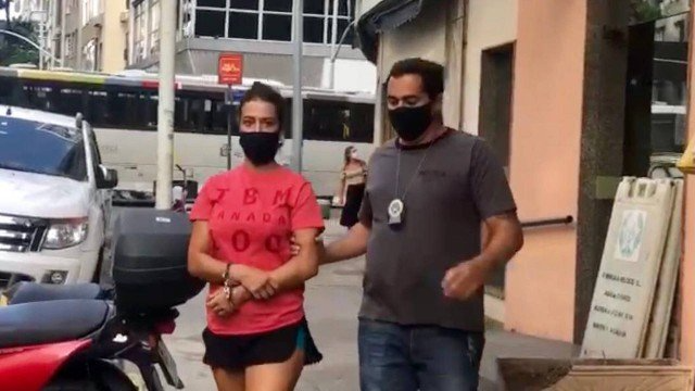 Lidia Nayara de Azevedo deixa a delegacia acompanhada de um policial civil
